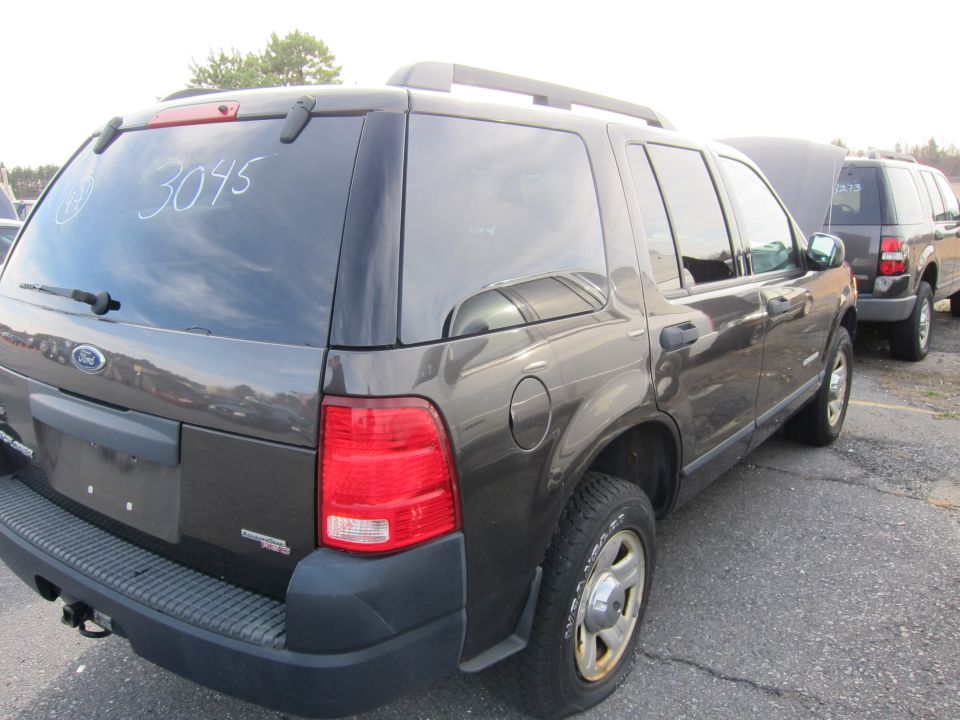 Dark gray Ford Explorer parked next to another Ford SUV with hood up. White numbers '3045' are written on the rear window