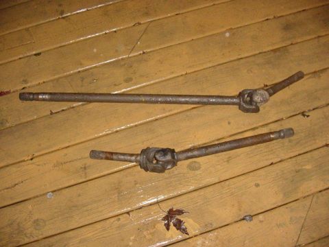 1992 Ford Bronco - Two drive shafts are shown lying on a weathered wooden surface, with a single fallen leaf nearby.