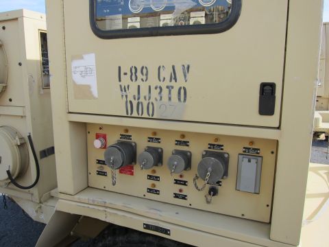 1991 Ford LTD Crown Victoria - Close-up of a military generator's control panel, stenciled identification numbers and various electrical connection points.
