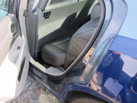 1991 Ford LTD Crown Victoria - The interior of a dark blue sedan is visible with the rear passenger door ajar, revealing leather seats and a partition.