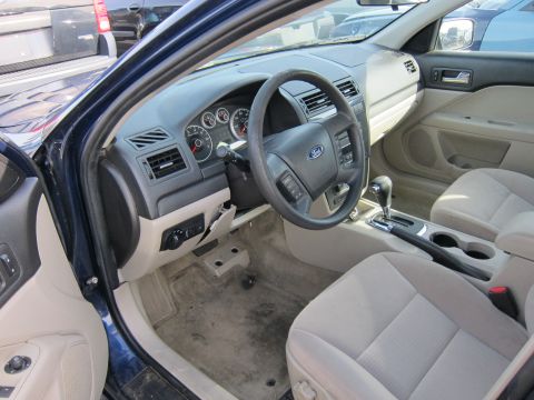 1991 Ford LTD Crown Victoria - The interior of a blue Ford Fusion is visible, tan cloth seats and a worn dashboard.