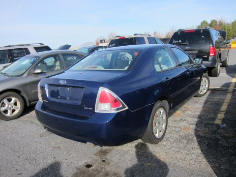 1991 Ford LTD Crown Victoria - A blue Ford sedan is parked in a lot with other vehicles under a clear sky.
