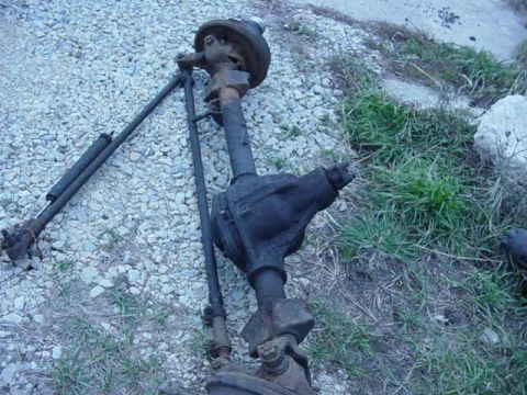 1992 Ford Bronco - Front axle assembly, likely from a truck or SUV, shown disassembled and lying on gravel.