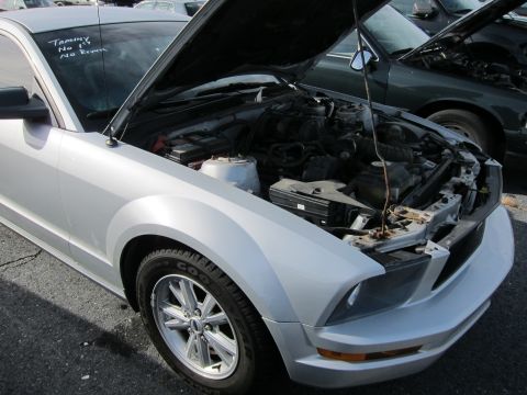 1991 Ford LTD Crown Victoria - Silver Ford Mustang with hood open, revealing the engine compartment. Another vehicle is visible behind it.
