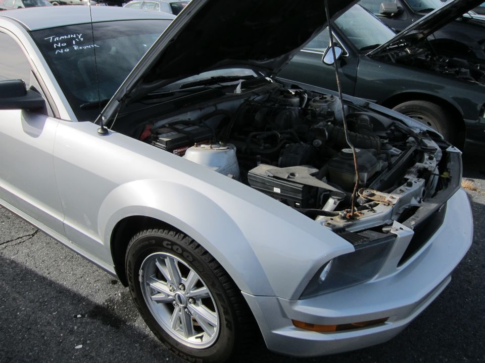 Silver Ford Mustang front quarter view with hood open, showing engine