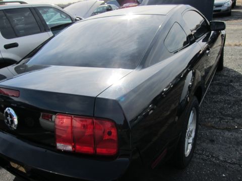 1991 Ford LTD Crown Victoria - Rear quarter view of a black coupe, showing its taillight and wheel. Other vehicles are visible in the background.