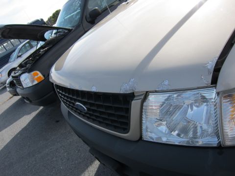 1991 Ford LTD Crown Victoria - Front view of a tan Ford Explorer parked next to a black Ford Explorer with its hood open.