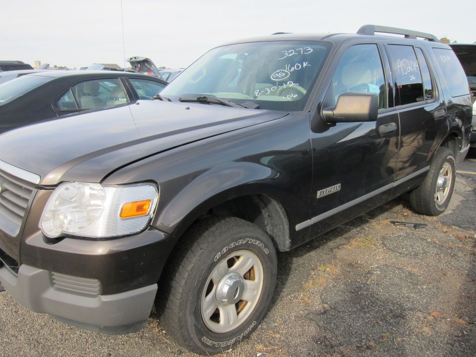 Dark gray Ford Explorer SUV parked in a lot, with writing on the windshield. Another car is visible to the left