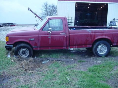 1992 Ford Bronco - A red 1992 Ford F250 pickup truck is stuck in the mud next to a barn.