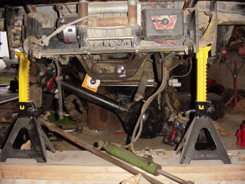 1992 Ford Bronco - Undercarriage of a 1992 Ford Bronco is supported by jack stands, revealing its winch and drivetrain.