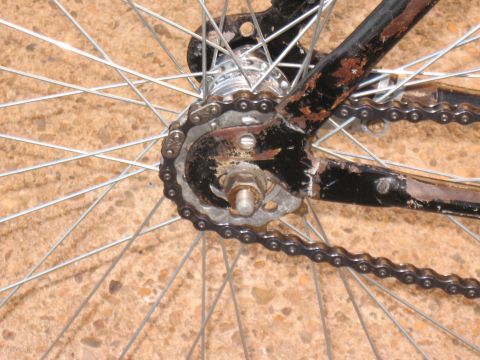 1994 Ford Bronco - Detail of a bicycle's rear wheel, showing the chain and sprocket, with visible rust on the black frame.