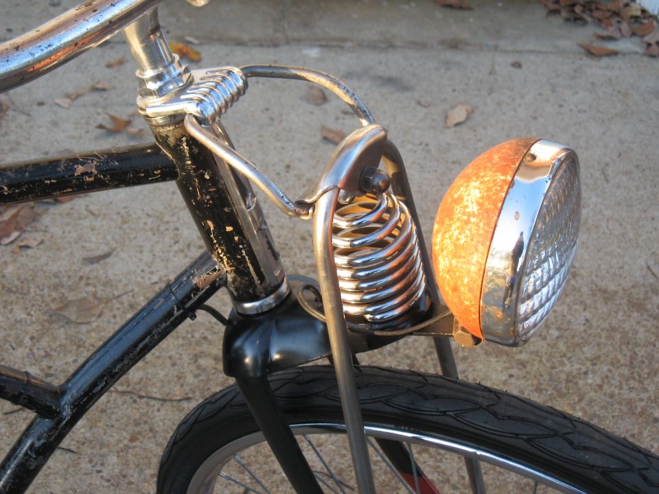 close-up of rusty vintage bicycle headlight with chrome trim and coil spring suspension