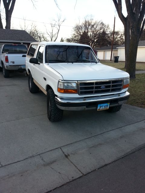 1996 Ford Bronco - A white Ford Bronco is parked on a driveway next to a white pickup truck.