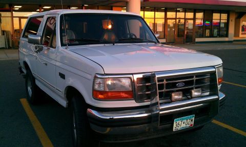 1996 Ford Bronco - This 1996 Ford Bronco is captured from a three-quarter front view, parked in a lot with a building in the background.