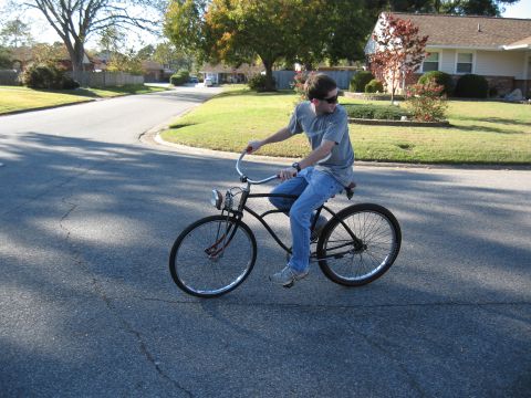 1994 Ford Bronco - A person rides a bicycle on a paved road in a residential neighborhood on a sunny day.