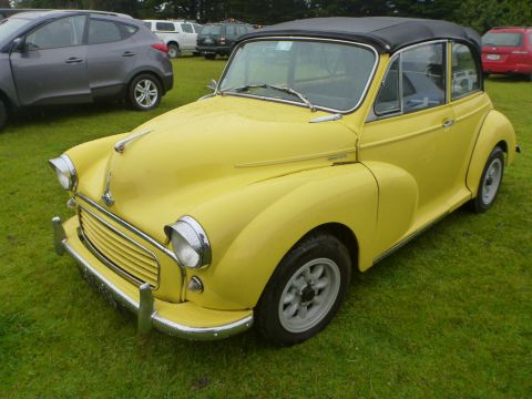 1969 Lincoln Continental - A yellow Morris Minor convertible is parked on a grassy field with other cars visible.