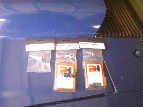 2003 Ford Crown Victoria - Three packages of automotive parts, including fittings and hardware, are displayed on a blue surface.