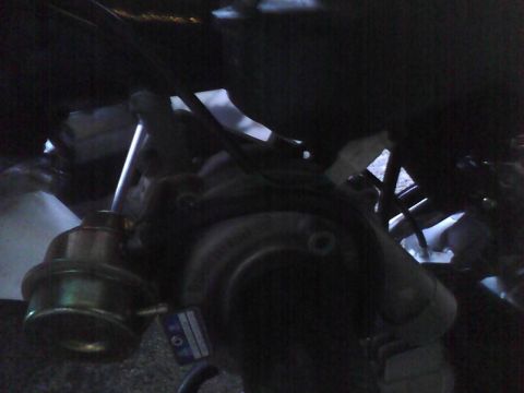2003 Ford Crown Victoria - Close-up of a turbocharger wastegate actuator, showing a label with some text and numbers.