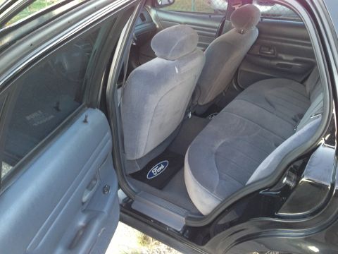 2001 Ford Crown Victoria - The interior of a car shows the rear seats and door panel, with a Ford logo on the floor mat.