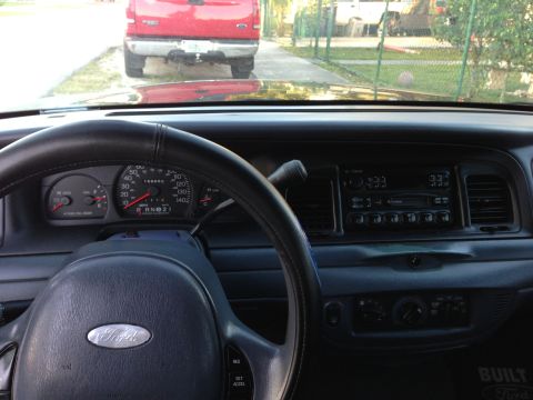 2001 Ford Crown Victoria - The dashboard and steering wheel of a Ford Crown Victoria are visible, with a red Ford F-150 truck in front.