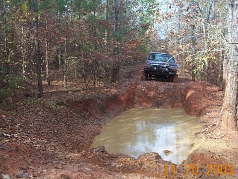 1986 Ford Bronco - A Ford Bronco navigates a muddy obstacle course in a forest setting.