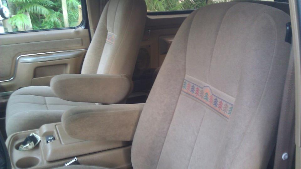 Vehicle interior showing front seats with armrests and a center console. Seats have a patterned fabric insert