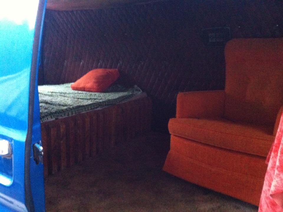 Interior of a van with a bed and orange armchair