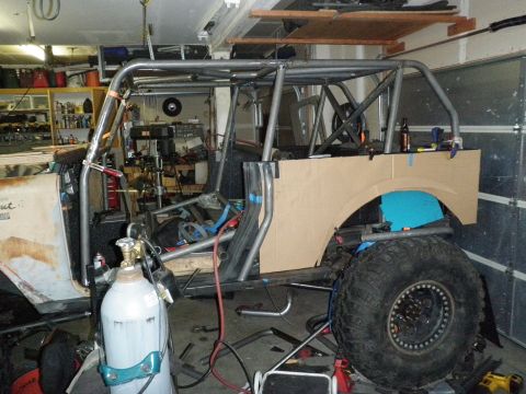1961 International Scout 800 - A custom roll cage is under construction inside a vehicle, with welding equipment nearby.