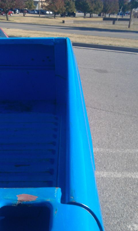 1973 Ford F-100 - A close-up view of the bed of a blue 1973 Ford F-100 pickup truck, revealing its ribbed floor and chipped paint.