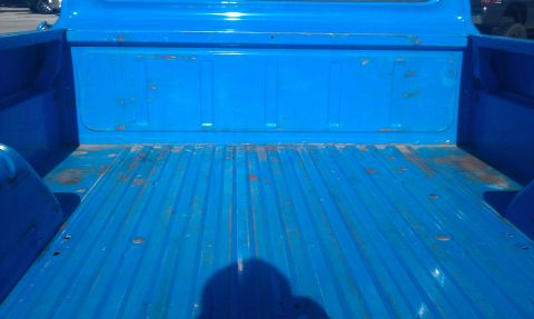 1973 Ford F-100 - The interior of a blue pickup truck bed shows a ribbed floor and some signs of wear and tear.