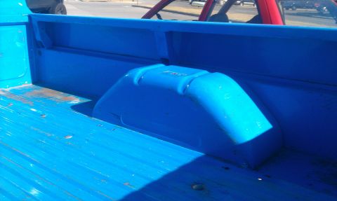 1973 Ford F-100 - Close-up view of the interior of a bright blue truck bed, showing the wheel well cover.