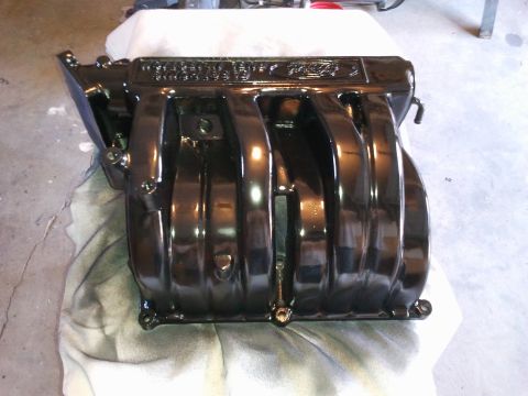 1990 Ford Bronco - A black Ford intake manifold is shown, with the "Ford" logo clearly visible on its upper surface.