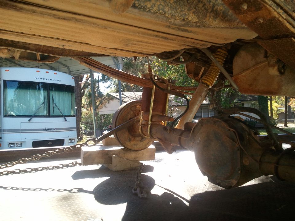 Undercarriage of a vehicle with leaf springs and differential, next to a Winnebago RV