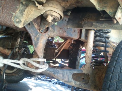 1990 Ford Bronco - Close-up of the undercarriage, showing suspension components and a tire, with a rope attached to the frame.
