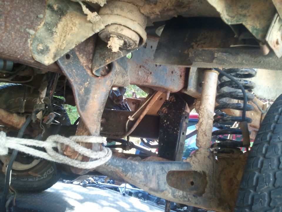 Undercarriage view of vehicle suspension and tire with rope tied to frame
