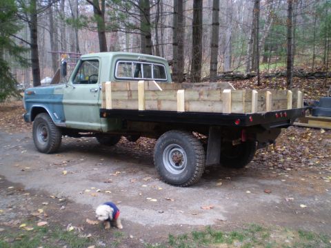 1979 Ford Bronco - A vintage Ford F-Series truck with a custom wooden flatbed is parked outdoors in a wooded area.