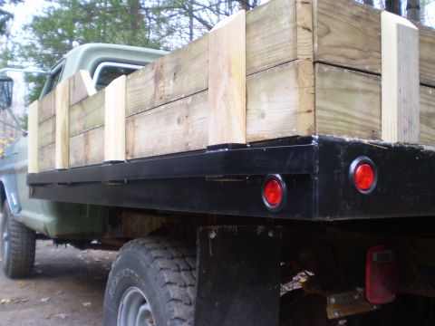 1979 Ford Bronco - A flatbed truck is seen from the side, loaded with wooden planks and red taillights.