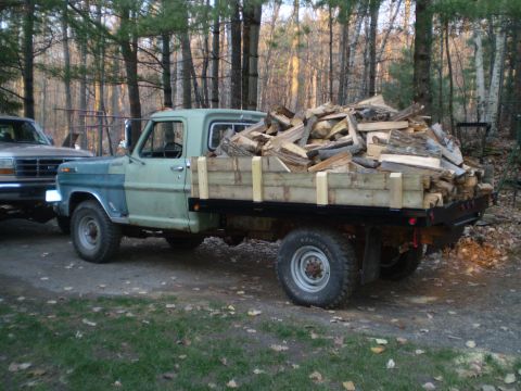 1979 Ford Bronco - A vintage Ford flatbed truck, likely from the 1970s, is seen from the side, heavily laden with cut firewood.