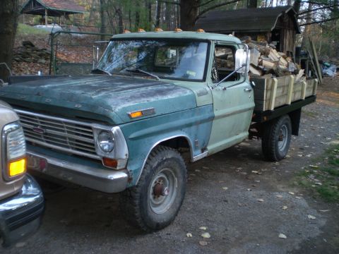 1979 Ford Bronco - This vintage Ford truck, likely from the early 1970s, is parked outdoors with a load of firewood in its flatbed.