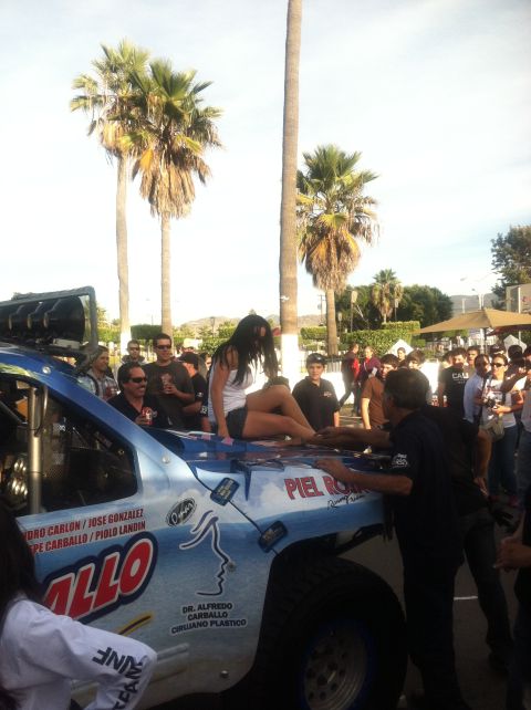 2004 Ford F-150 - A crowd gathers around a light blue off-road truck, possibly a race vehicle, with a woman posing on its hood.