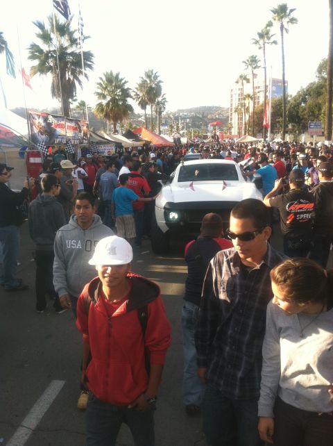 2004 Ford F-150 - A white pickup truck is the focus of attention at a busy street fair with many spectators.