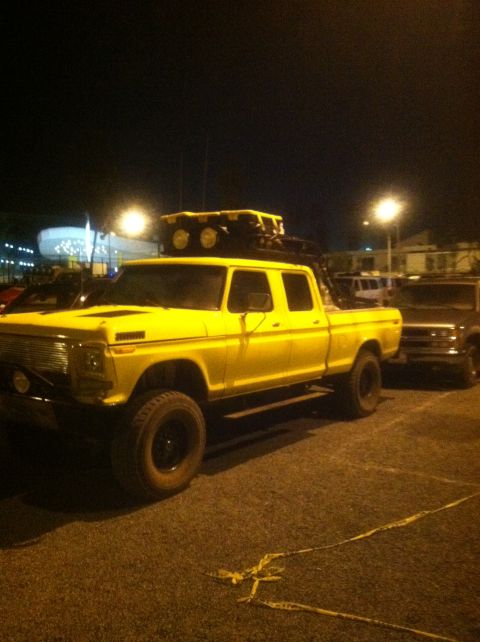2004 Ford F-150 - This lifted, yellow crew cab pickup truck is equipped with a roof rack and off-road tires, suggesting it is ready for adventure.