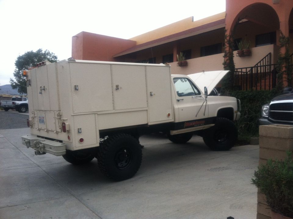 Service truck with utility body, large tires, and hood open