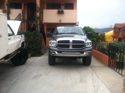 2004 Ford F-150 - A gray Dodge Ram pickup truck is parked in front of a building, with a white truck to its left.