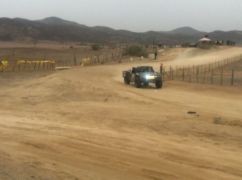 2004 Ford F-150 - A truck races down a dusty track in a barren, hilly area.