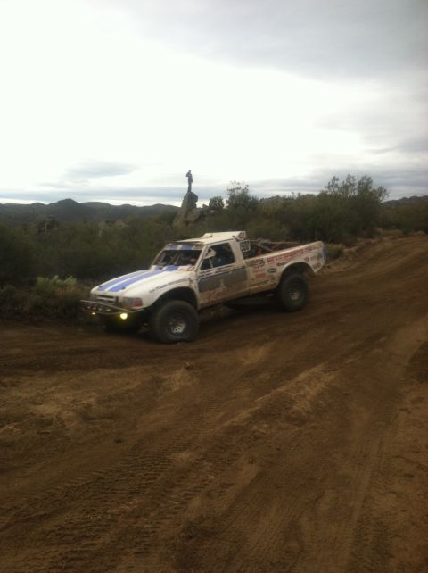 2004 Ford F-150 - This modified truck, likely from the late 1980s, navigates a dusty off-road course under a cloudy sky.