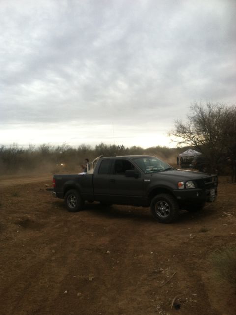 2004 Ford F-150 - Dark gray 2004 Ford F-150 pickup truck parked in a dusty, outdoor area with trees in the background.