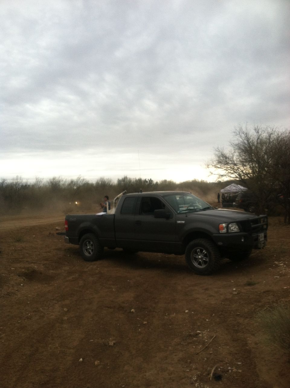 2004 Ford F-150 pickup truck parked on dirt with trees and cloudy sky