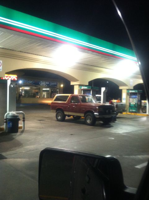 2004 Ford F-150 - A red and tan SUV is parked at a gas station under bright lights at night.