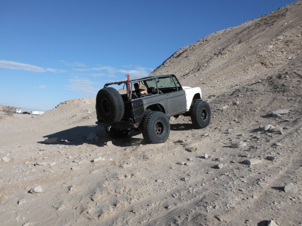 off-road SUV with spare tire on back, driving on a dirt hill